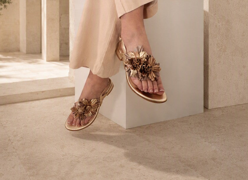 Close-up of Paloma sandal worn, showing floral corsage detail on foot