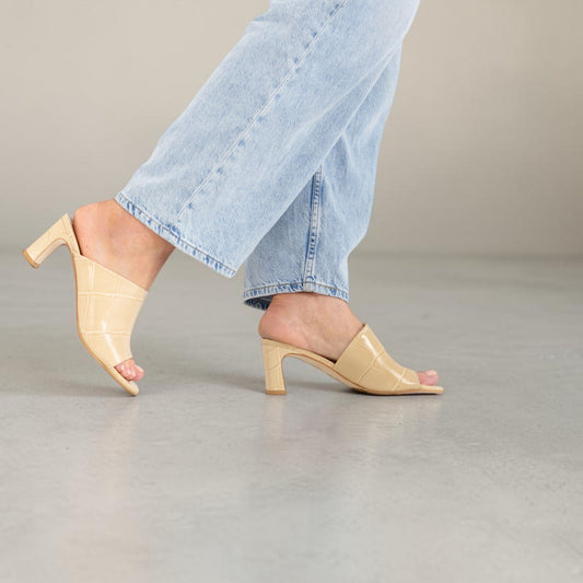 Model wearing Alba Champagne Sand croc-embossed leather mules, lifestyle shot, by Estela